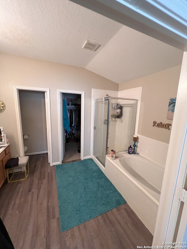 full bathroom with lofted ceiling, independent shower and bath, wood-type flooring, a textured ceiling, and toilet