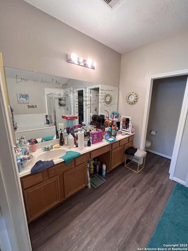 full bathroom with hardwood / wood-style flooring, toilet, shower with separate bathtub, a textured ceiling, and vanity