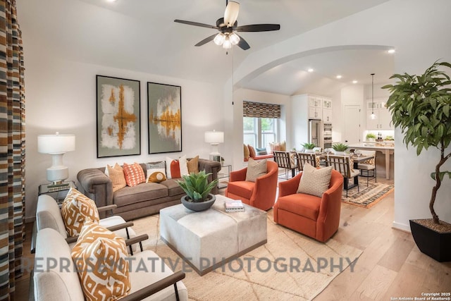 living room with ceiling fan, light hardwood / wood-style floors, and lofted ceiling