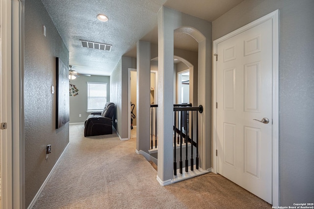 hallway featuring light carpet and a textured ceiling