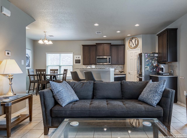 living room featuring light tile patterned flooring, a textured ceiling, and a notable chandelier