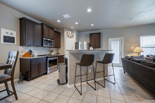 kitchen featuring dark brown cabinetry, stainless steel appliances, and a kitchen island