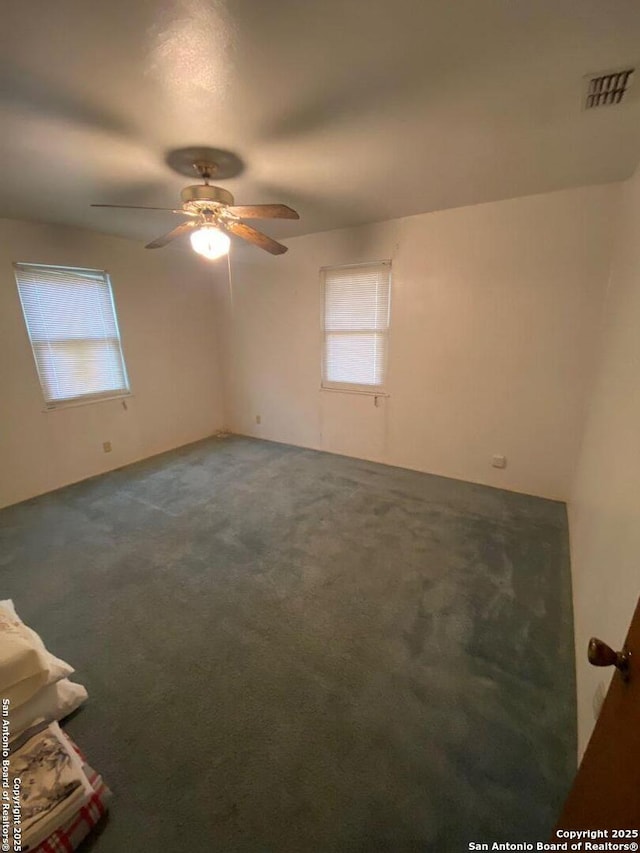 carpeted spare room featuring ceiling fan and visible vents