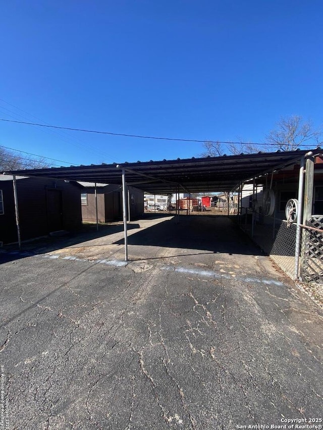 view of parking / parking lot with a carport and fence