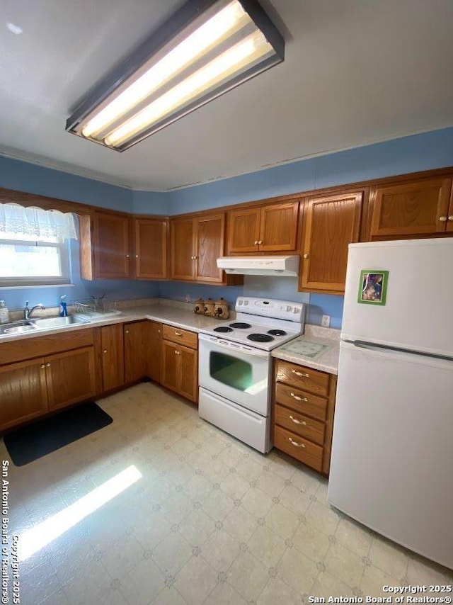 kitchen with under cabinet range hood, white appliances, light countertops, brown cabinets, and light floors