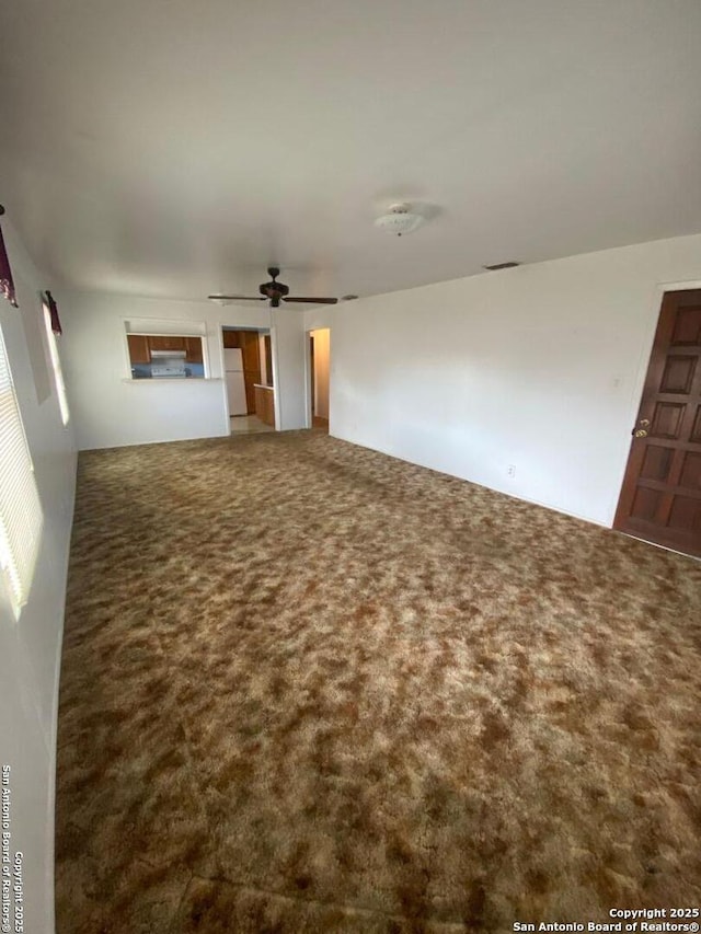 unfurnished living room featuring carpet floors, visible vents, and a ceiling fan