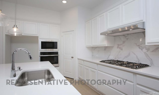 kitchen with sink, decorative light fixtures, stainless steel appliances, white cabinets, and decorative backsplash