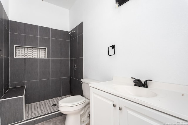 bathroom featuring toilet, a tile shower, tile patterned flooring, and vanity