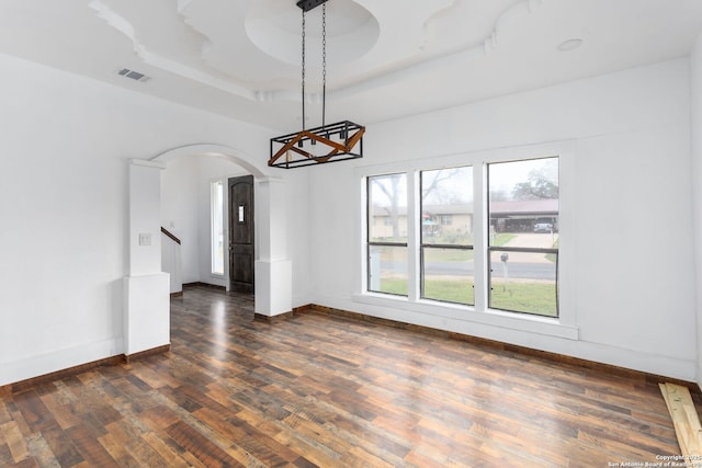 unfurnished dining area featuring a tray ceiling and dark hardwood / wood-style floors