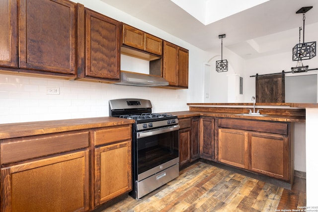 kitchen with sink, gas stove, backsplash, decorative light fixtures, and a barn door