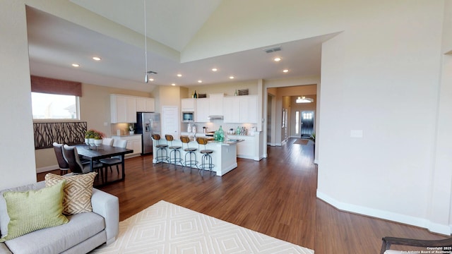 living room with high vaulted ceiling and dark wood-type flooring