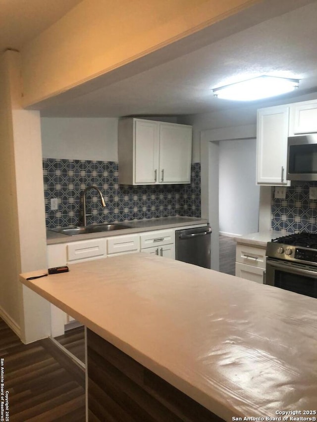 kitchen with sink, stainless steel appliances, dark wood-type flooring, white cabinets, and tasteful backsplash