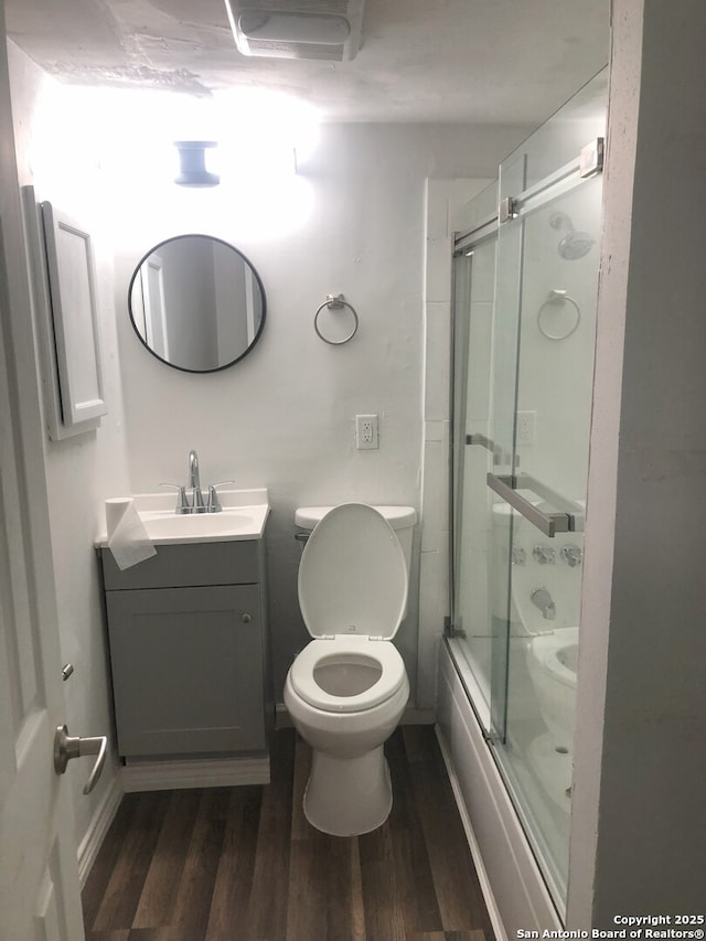 full bathroom with toilet, hardwood / wood-style flooring, shower / bath combination with glass door, and vanity