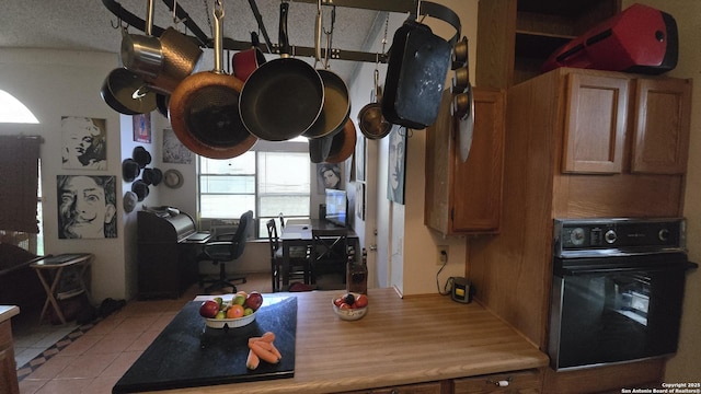 kitchen with light tile patterned floors, brown cabinetry, and black oven