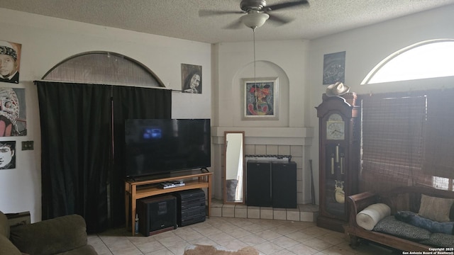 living area with a textured ceiling, ceiling fan, and light tile patterned flooring