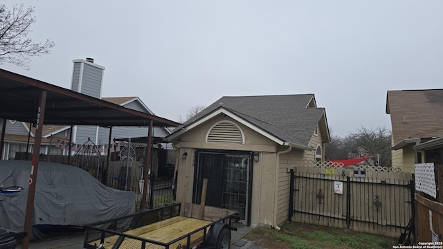 exterior space featuring a shingled roof, a chimney, and fence private yard