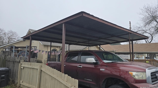 view of parking with a detached carport and fence