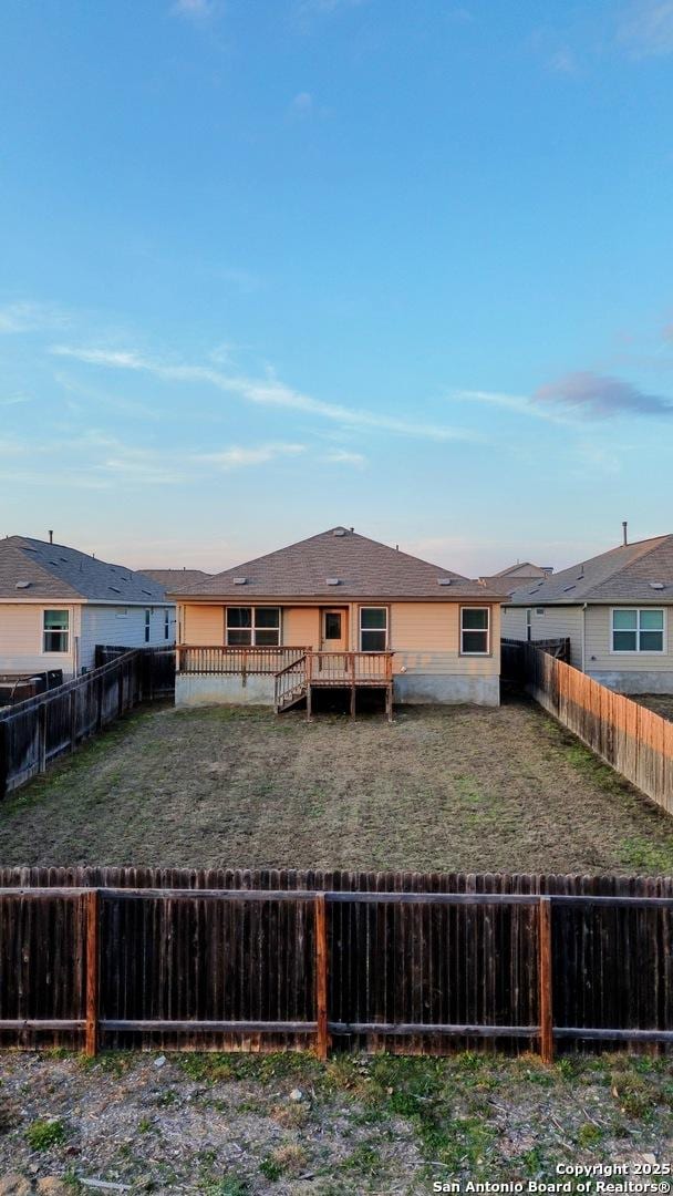 back of property featuring a residential view, a fenced backyard, a yard, and a deck