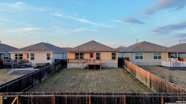 back of property at dusk featuring a fenced backyard, a wooden deck, and a residential view