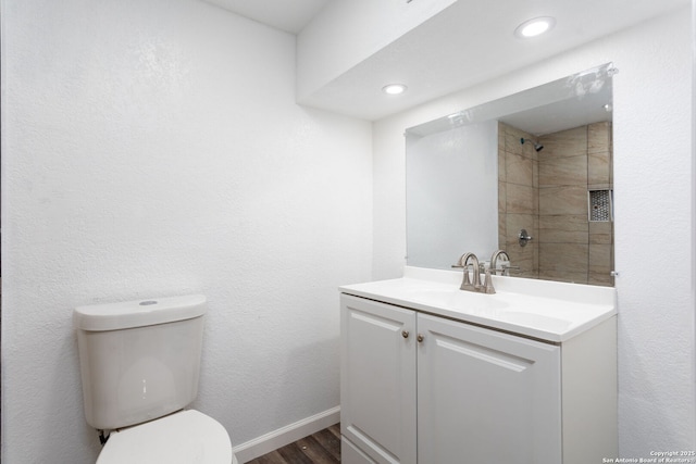 bathroom with vanity, tiled shower, toilet, and hardwood / wood-style floors