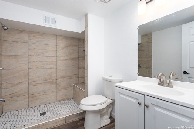 bathroom with toilet, vanity, and tiled shower