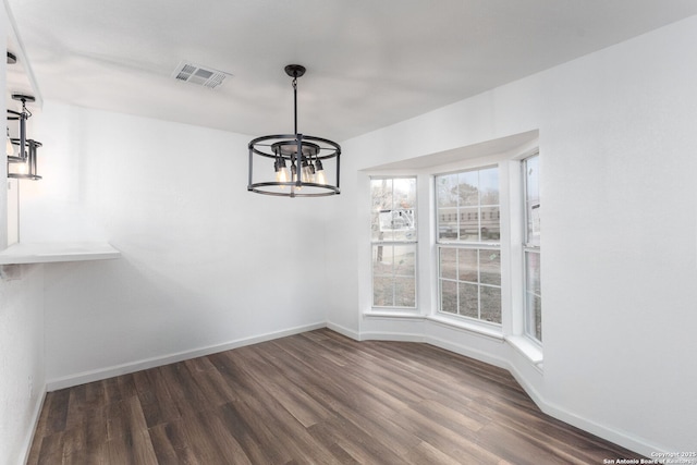 unfurnished dining area featuring dark hardwood / wood-style floors and an inviting chandelier