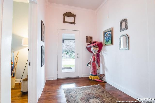 doorway to outside featuring crown molding, baseboards, and wood finished floors