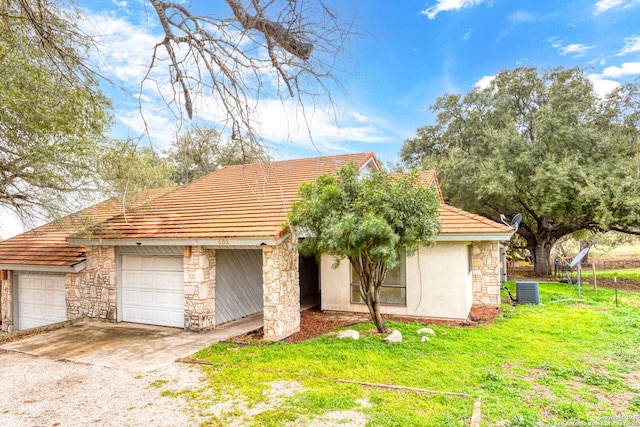 exterior space with a front yard, central AC unit, and a garage