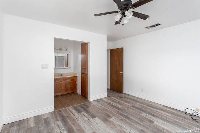 unfurnished bedroom with connected bathroom, light hardwood / wood-style floors, sink, and ceiling fan