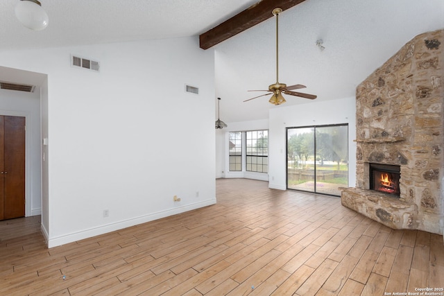 unfurnished living room with a fireplace, beamed ceiling, light hardwood / wood-style floors, and a textured ceiling