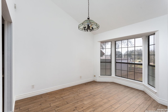 unfurnished room featuring an inviting chandelier, light hardwood / wood-style floors, and lofted ceiling