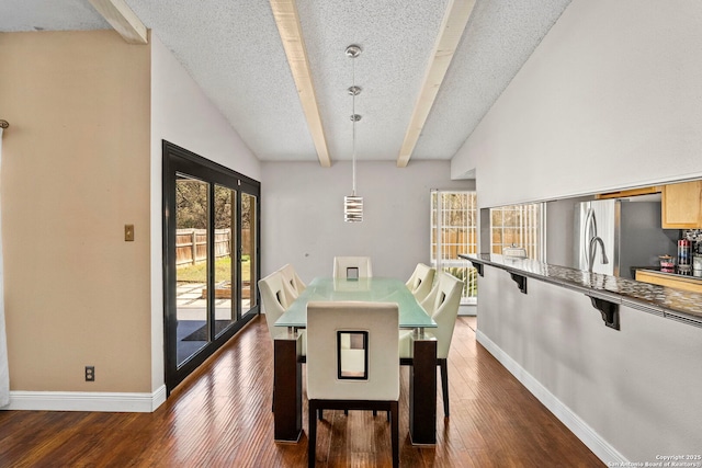 dining room with dark wood-style floors, vaulted ceiling with beams, a textured ceiling, and baseboards