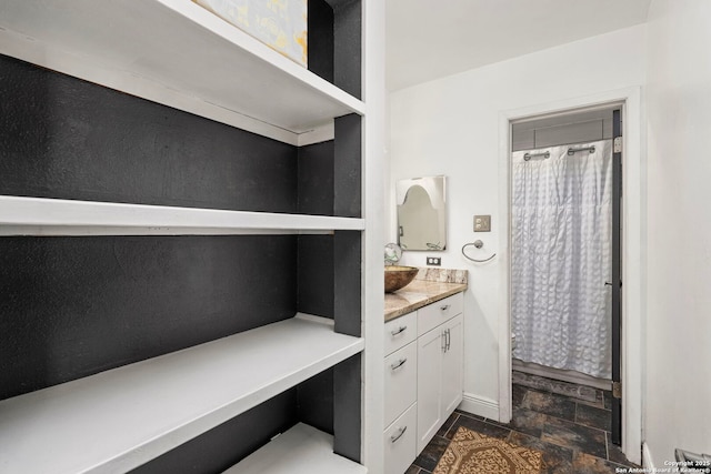 full bathroom with stone finish flooring, baseboards, a shower with curtain, and vanity