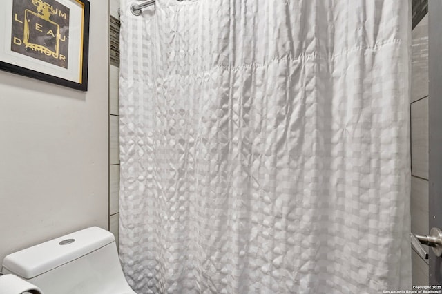 bathroom with curtained shower and toilet