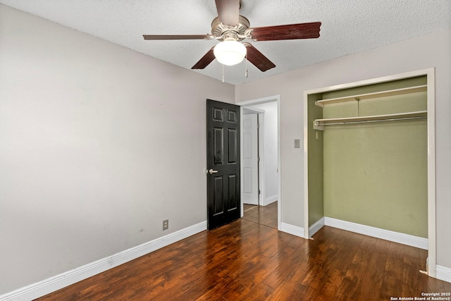 unfurnished bedroom featuring a closet, a textured ceiling, baseboards, and wood finished floors