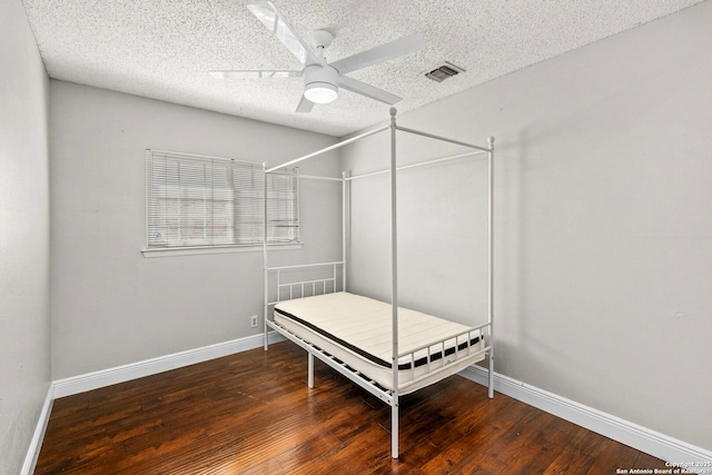 bedroom with baseboards, visible vents, wood-type flooring, and a textured ceiling