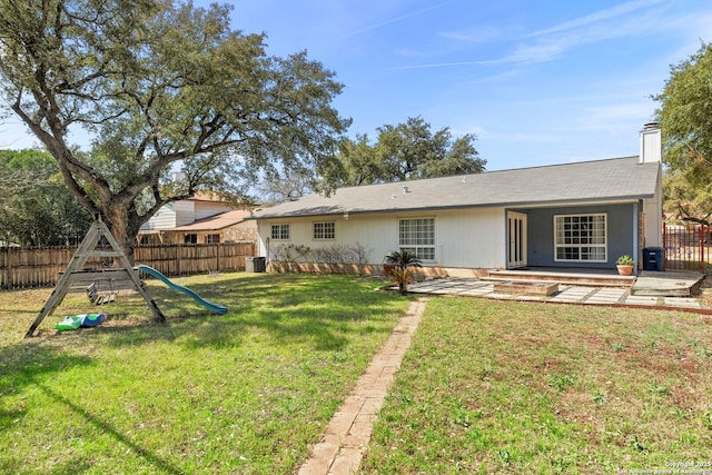 back of house with a playground, a chimney, a yard, a fenced backyard, and a patio area