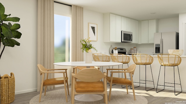 kitchen with light wood-type flooring, appliances with stainless steel finishes, white cabinets, and a breakfast bar area