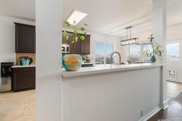kitchen with dark brown cabinets, sink, pendant lighting, and a textured ceiling
