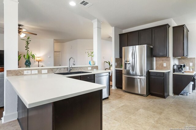 kitchen featuring appliances with stainless steel finishes, tasteful backsplash, sink, decorative columns, and kitchen peninsula