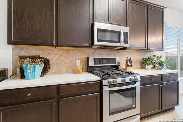 kitchen with light tile patterned flooring, dark brown cabinets, stainless steel appliances, and backsplash
