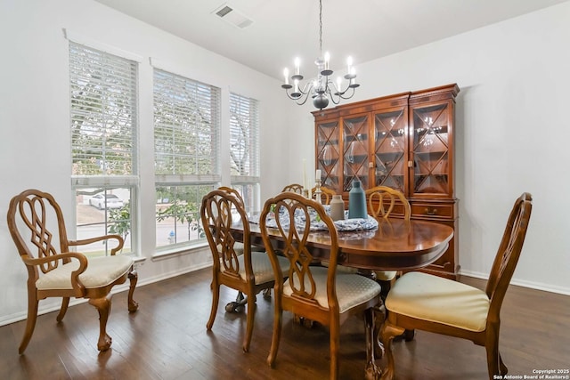dining area with dark wood-type flooring, an inviting chandelier, and plenty of natural light