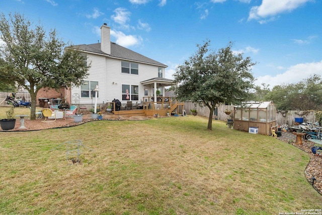 back of property with a lawn, an outbuilding, and a deck