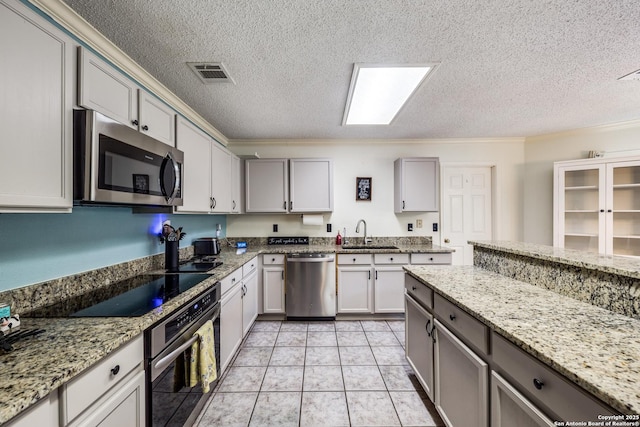 kitchen with appliances with stainless steel finishes, sink, light tile patterned floors, light stone counters, and gray cabinets