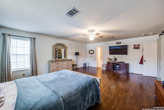 bedroom with ceiling fan, dark wood-type flooring, and a textured ceiling