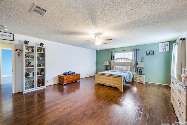 bedroom with ceiling fan, dark wood-type flooring, and a textured ceiling