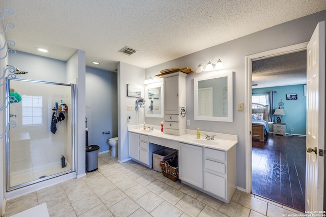 bathroom featuring vanity, walk in shower, a textured ceiling, tile patterned flooring, and toilet