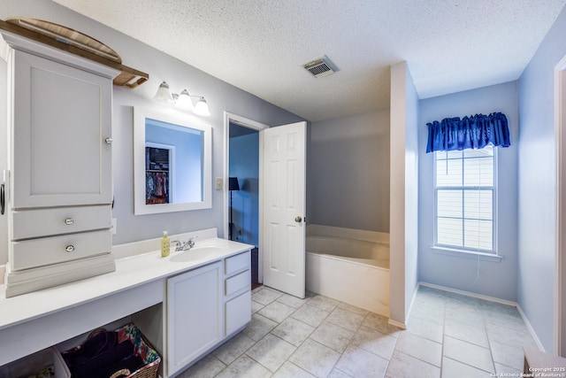 bathroom with a washtub, tile patterned floors, vanity, and a textured ceiling