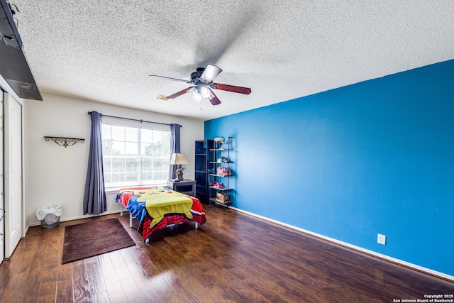 bedroom with ceiling fan, a closet, dark wood-type flooring, and a textured ceiling