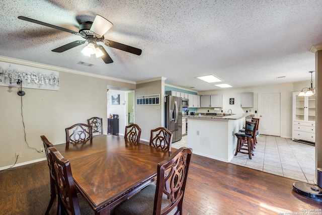 dining space with a textured ceiling, crown molding, and wood-type flooring